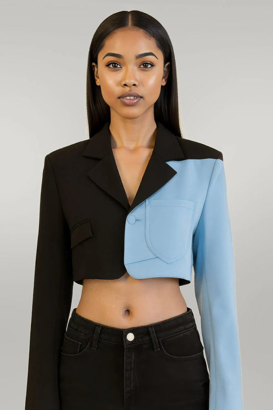Woman wearing a black and blue cropped jacket against a plain background
