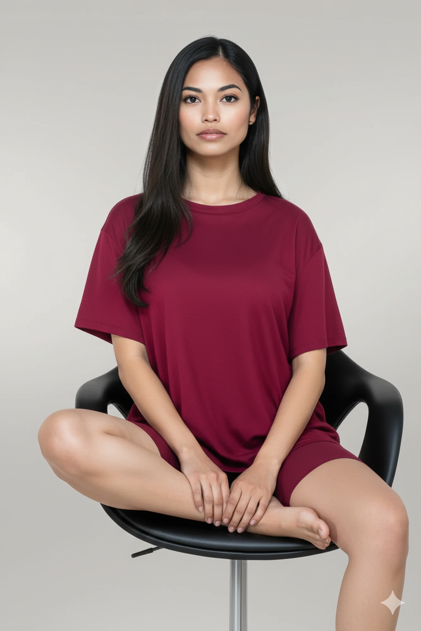 Woman wearing a maroon t-shirt sitting on a black chair against a plain background