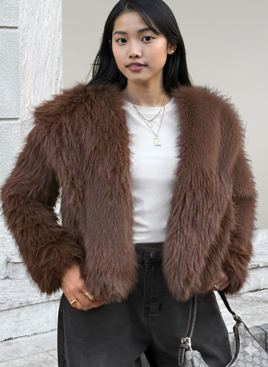 Woman wearing a brown fluffy jacket against a light-colored wall.