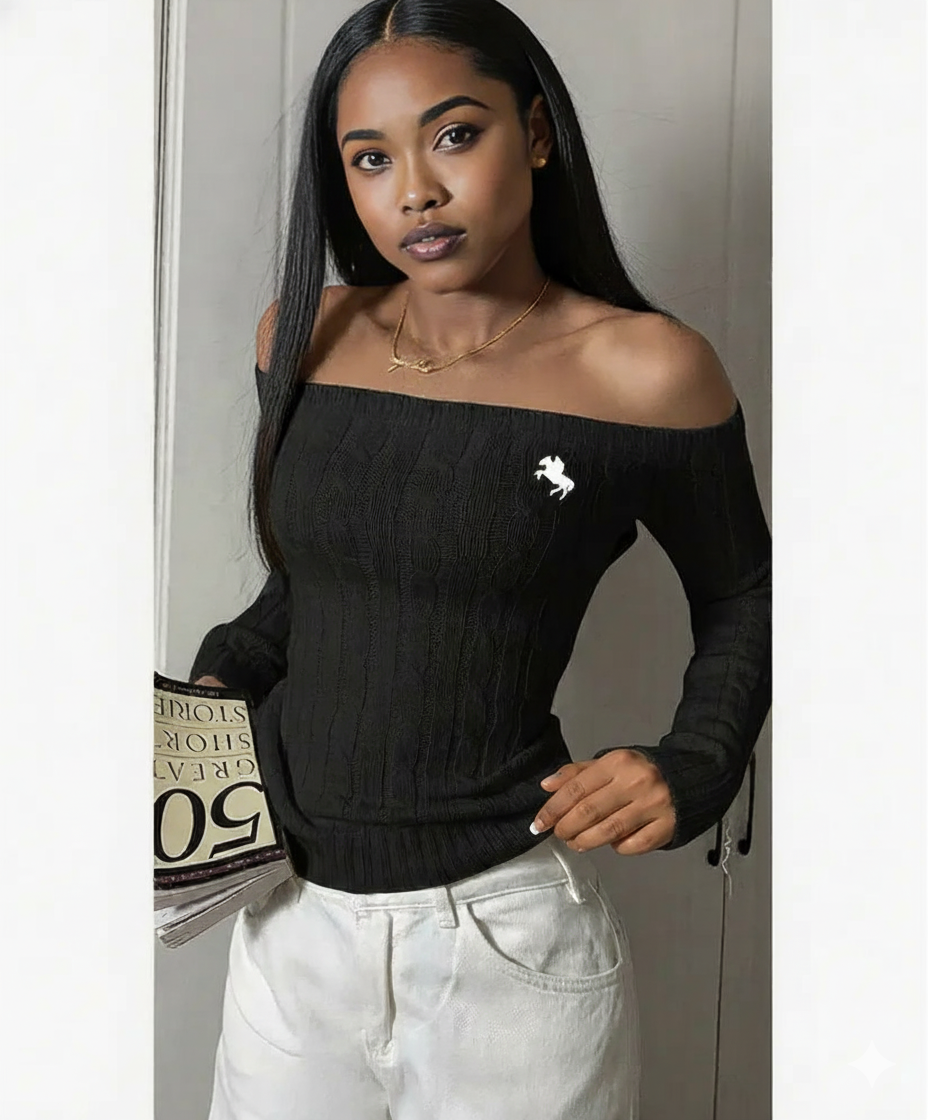 Woman wearing a black off-shoulder sweater with a logo, holding a magazine.